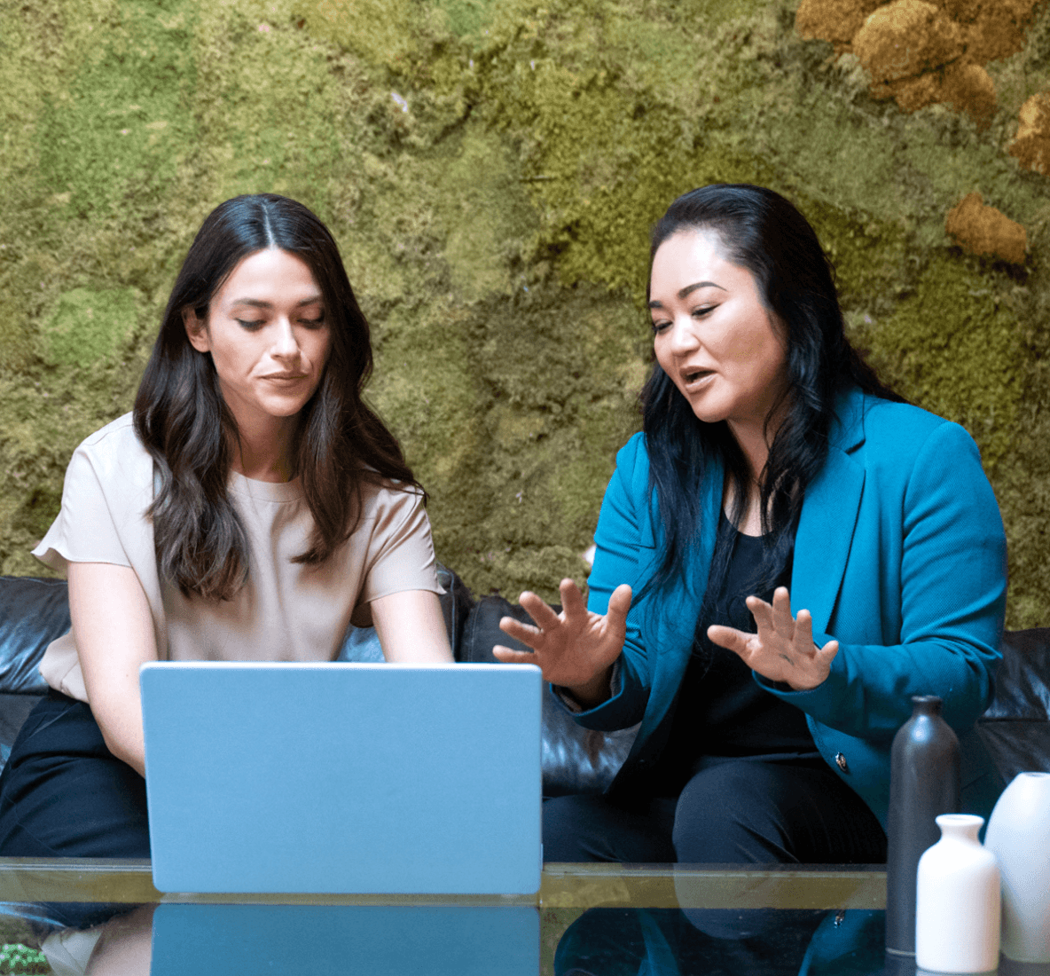 Imagem de duas mulheres sentadas em frente a um laptop, discutindo.