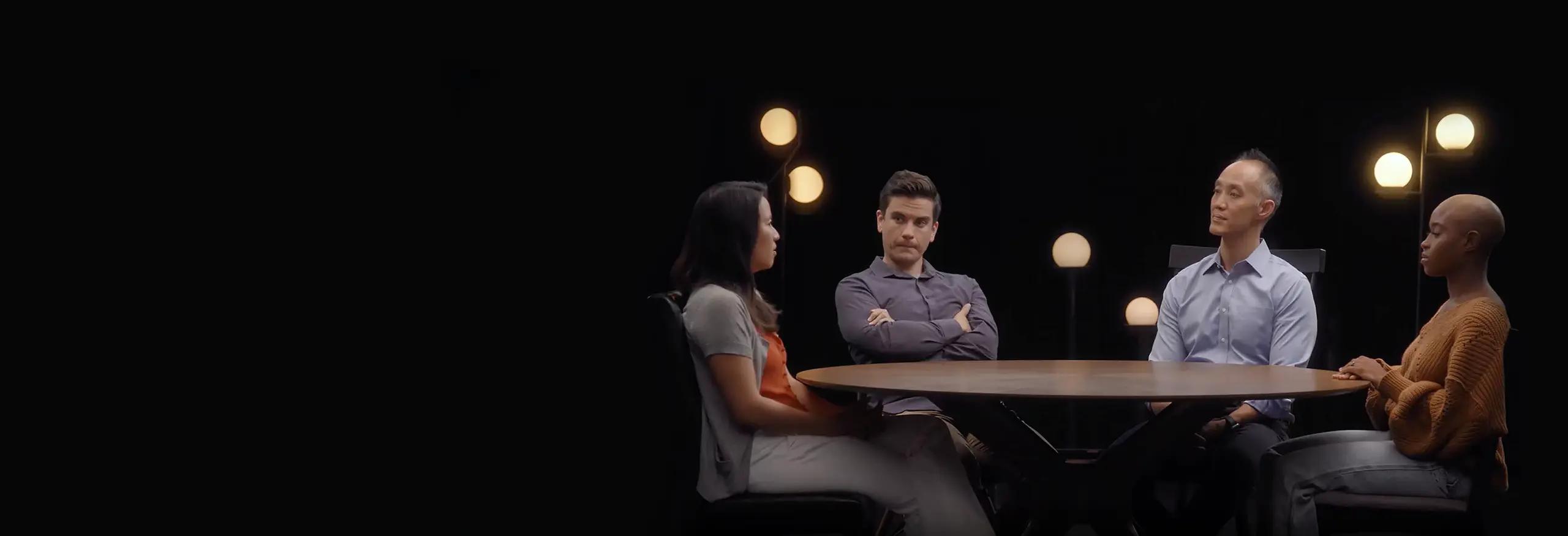 Imagem de quatro pessoas sentadas ao redor de uma mesa discutindo.